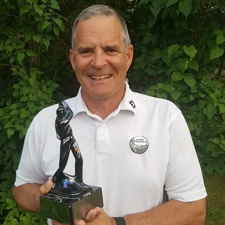 Tapani Saarentola hymyilee valkoisessa pikeepaidassa ja pitelee golfaajaa esittävää pokaalia